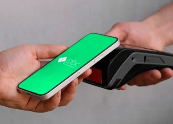 Mão segura celular com tela verde do Pix perto de maquininha de cartão preta.