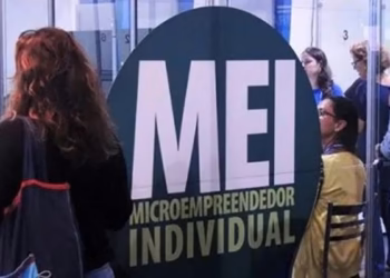 Pessoas em um espaço de atendimento ao microempreendedor individual, com painel azul com a sigla MEI, público do Desenrola MEI Pequeno Valor